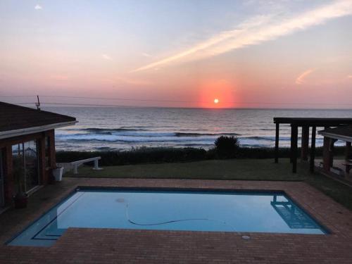 a swimming pool with a view of the ocean at sunset at Platinum View Ocean Breeze in Widenham