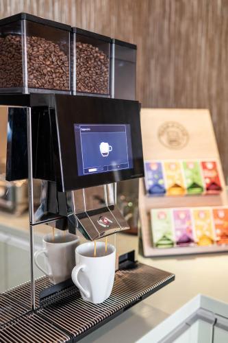 a coffee machine with cups and a computer on a counter at Hotel Ganslhof - Adults only in Salzburg