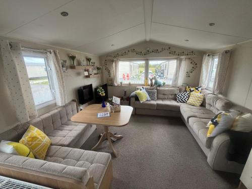 a living room with couches and a table at KPC-HELLYEAH caravan in Humberston