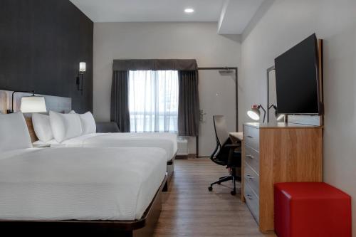 a hotel room with two beds and a flat screen tv at Canalta Cochrane in Cochrane