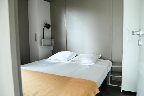 a bedroom with a bed with white sheets and pillows at Camping Les Amandiers in Collioure