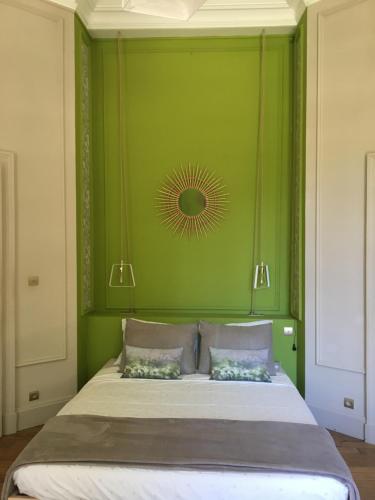 a green bedroom with a large bed with two pillows at La Guérimande in Loriol-sur-Drôme