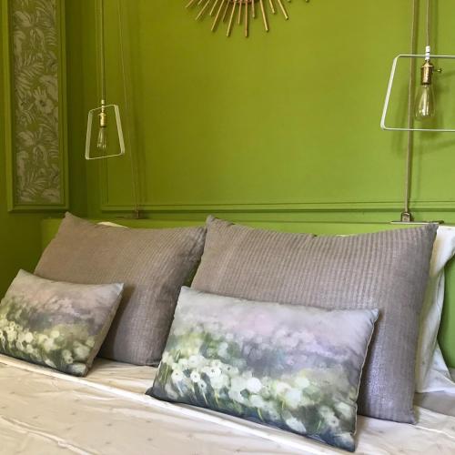 - un lit avec trois oreillers et un mur vert dans l'établissement La Guérimande, à Loriol-sur-Drôme