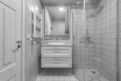 a white bathroom with a sink and a shower at 2BR Apartment in the Heart of Selfoss in Selfoss