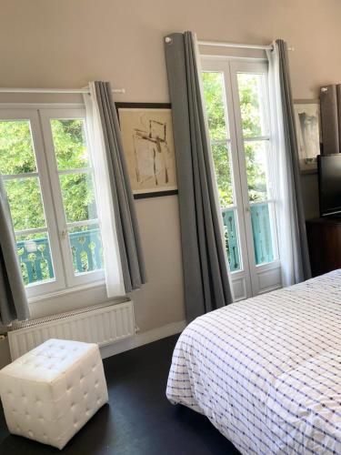 une chambre avec deux fenêtres et un lit avec un tabouret dans l'établissement Petite maison charmante proche Bords de Marne, à Saint-Maur-des-Fossés