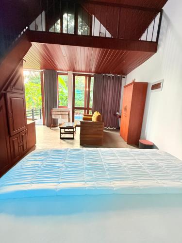a bedroom with a bed and a chair and windows at Calm Side Villa Hikkaduwa in Hikkaduwa