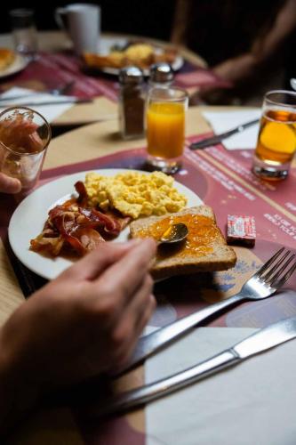 Un plato de desayuno con huevos, tocino y tostadas. en Grand Magic Hotel Marne La Vallée, en Magny-le-Hongre