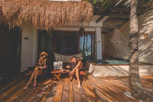 two people sitting on the deck of a house at The Beach Tulum Hotel in Tulum