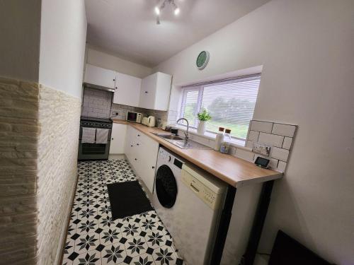 een kleine keuken met een wastafel en een vaatwasser bij The Trackside Cottage in Carlin How