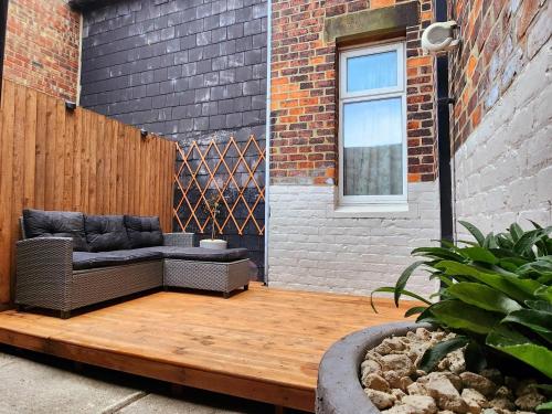 een patio met een bank op een houten terras bij The Trackside Cottage in Carlin How