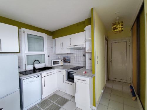 une cuisine avec des armoires blanches et un évier dans l'établissement Appart T2 en front de mer - chambre séparée -parking- terrasse couverte, au Barcarès