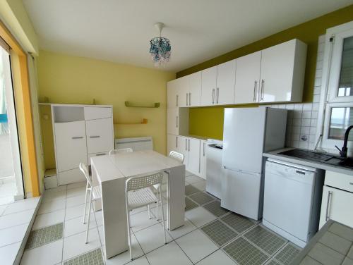 - une cuisine avec des appareils blancs, une table et des chaises dans l'établissement Appart T2 en front de mer - chambre séparée -parking- terrasse couverte, au Barcarès