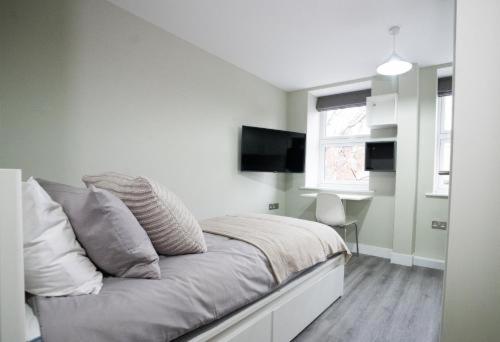 a white bedroom with a bed and a television at Ryegate House Colchester in Colchester
