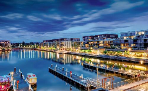 a river with buildings and a marina at night at Prestige Waterfront Apartment in Kingston, ACT in Canberra