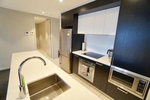 a kitchen with a sink and a stainless steel refrigerator at Prestige Waterfront Apartment in Kingston, ACT in Canberra