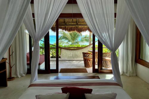 a bedroom with a bed with white drapes at The Beach Tulum Hotel in Tulum