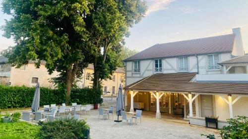 a courtyard with tables and chairs in front of a building at Hôtel du Cheval Blanc - Paris Marne La Vallée in Jossigny