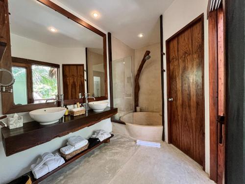 a bathroom with two sinks and a tub and a mirror at The Beach Tulum Hotel in Tulum