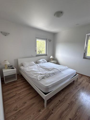 a white bedroom with a large bed and a window at Apartment Milna Dante in Milna