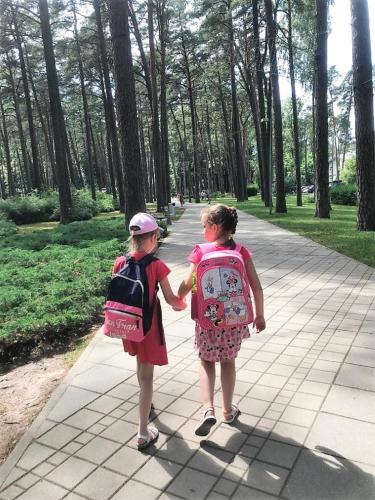 two young girls walking down a sidewalk holding hands at Apartament Dzintari in Jūrmala