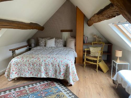 a bedroom with a bed and a chair in a attic at Maison des Roses in Fontaine-Chaâlis