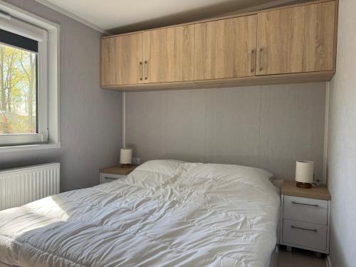 a bedroom with a bed with white sheets and cabinets at XaBo nr 133 op 5 sterren camping De Pallegarste in Mariënberg
