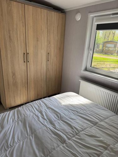 a bedroom with a white bed and a window at XaBo nr 133 op 5 sterren camping De Pallegarste in Mariënberg