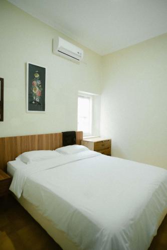Una cama blanca grande en un dormitorio con ventana. en Indise House at Hamsa Putih Yogyakarta, en Yogyakarta