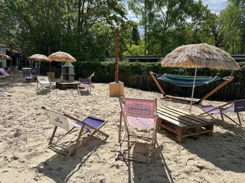 a beach with chairs and umbrellas and a hammock at Skorzęcin Przytulny Zakątek in Skorzęcin
