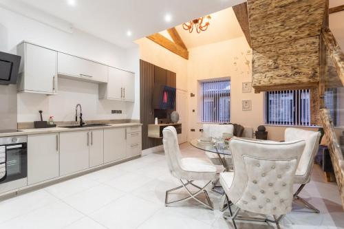 a kitchen with a glass table and white chairs at Bradford Luxury Central Apartment with Jacuzzi in Bradford