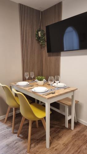 a dining room table with chairs and a television on a wall at Boxford Lodge - Serviced Apartment in Bracknell, near Ascot & Windsor, Free Parking in Bracknell