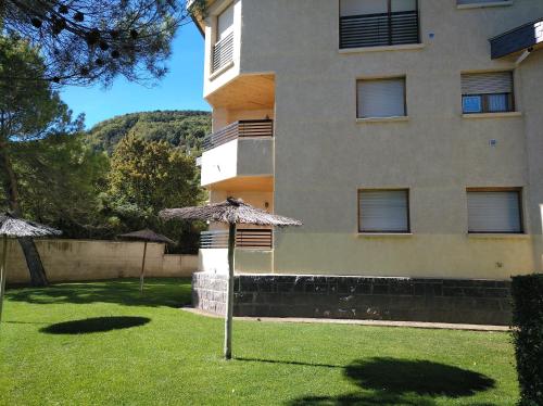 a building with a grass yard with an umbrella at Tena Biescas Tourist Home in Biescas