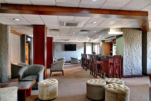 a waiting room with chairs and tables and a bar at Holiday Inn - Harare by IHG in Harare