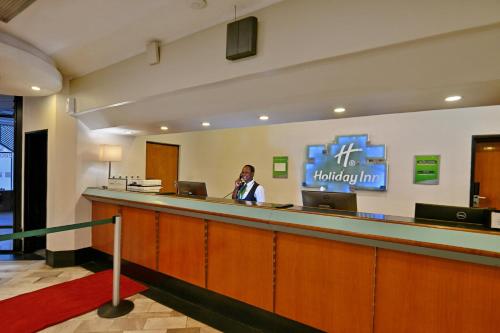 a man talking on a phone at a reception desk at Holiday Inn - Harare by IHG in Harare