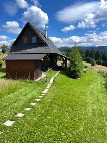 a house on a grassy hill with a path leading to it at Chata Drevenica Orava in Oravská Lesná