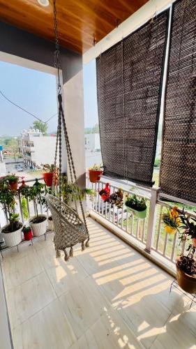 a porch with a swing and some potted plants at Dhyani Residence in Nakraunda