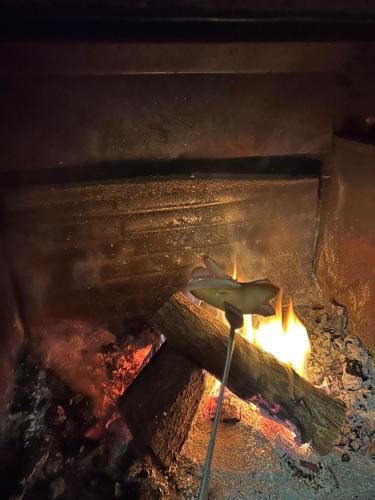 a piece of meat is cooking over a fire at Rustico Cascina Val Malvaglia in Malvaglia