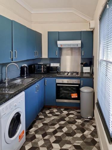 a kitchen with blue cabinets and a washing machine at Evo Stays - 2 bedroom, 2 mins walk to Station in Gravesend