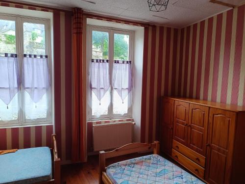 une chambre avec un lit et une commode et deux fenêtres dans l'établissement La Maison de Falaise, à Falaise