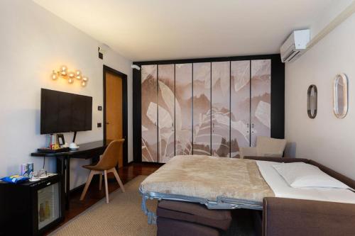 a bedroom with a bed and a desk and a television at Hotel Ancora in Verbania