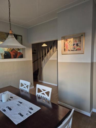 a dining room with a table and white chairs at Windalens på Österlen in Tomelilla