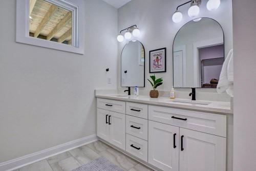 a white bathroom with two sinks and two mirrors at Good Vibes - Ocean View Home With Elevator in Surf City