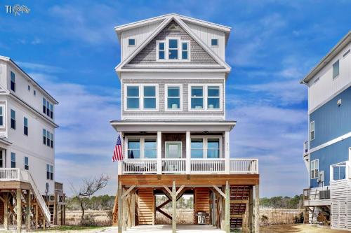 a house with a wrap around porch with an american flag at Dog Friendly | Waterfront | Surf City, NC | 2 Master Suites | Elevator in Surf City