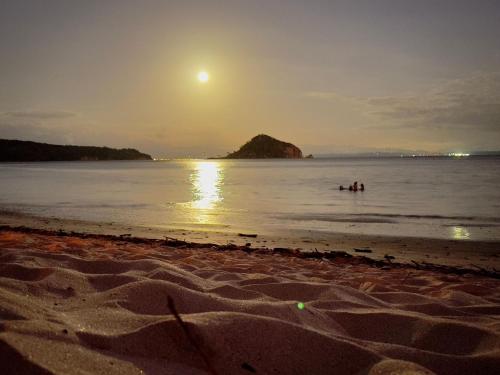 a group of people swimming in the ocean at sunset at Villas Roma Del Mar in Playa Naranjo