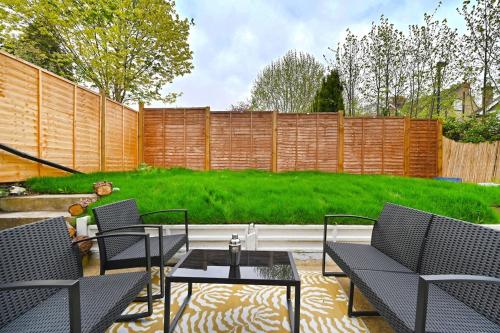 a patio with chairs and a table and a fence at South Croydon, garden maisonette, free parking, Gatwick accessible in Purley