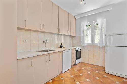 a kitchen with white cabinets and a sink and a refrigerator at Apartments Dončić in Kotor