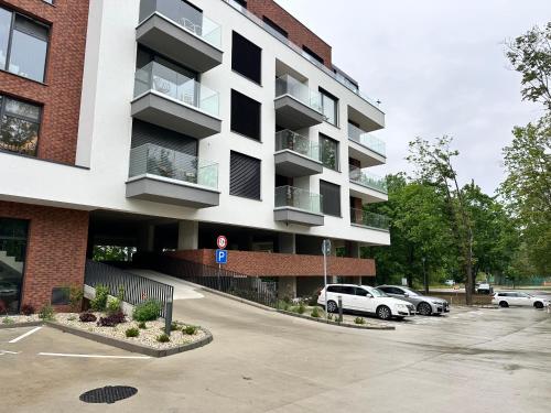 an apartment building with cars parked in a parking lot at Apartman Pinia in Banka