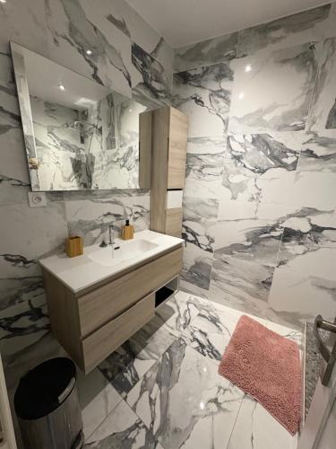 La salle de bains est pourvue d'un lavabo et d'un mur en marbre. dans l'établissement Appartement 2 chambres proche plage, à Marseille