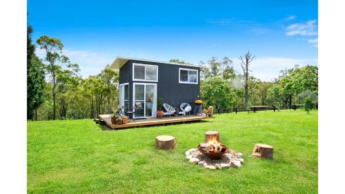 a tiny house in a field with trees in the background at Malniri Park by Tiny Away in Wilberforce
