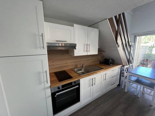 - une cuisine avec des placards blancs, un évier et une table dans l'établissement DELPHEAPOLIS Joli T2 mezzanine climatisé Richelieu Cap d'Agde, au Cap d'Agde